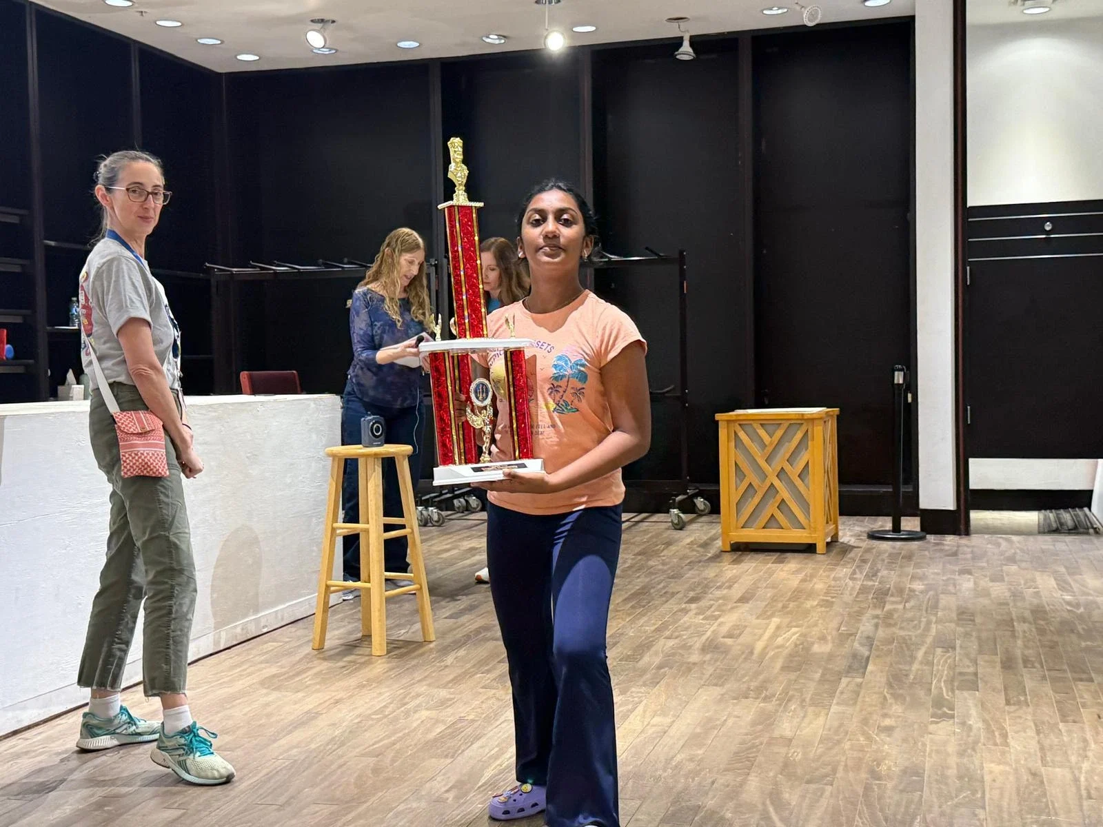 A young female chess student proudly holding a large red and gold chess tournament trophy from TCA region v scholastic championship houston